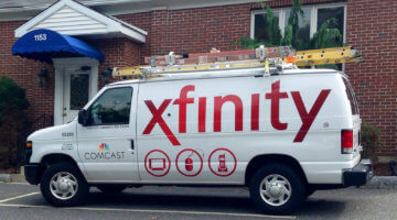 Photo of a white Comcast service van parked in front of a brick building