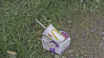 A photo of McDonald's food wrappers and drink cup discarded in a lawn