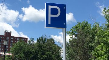 A sign displaying a white letter P on a blue field set against a clear blue sky at a parking lot in Bridgeville, PA.